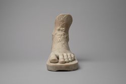 Linker Fuß mit Sandale auf Plinthe