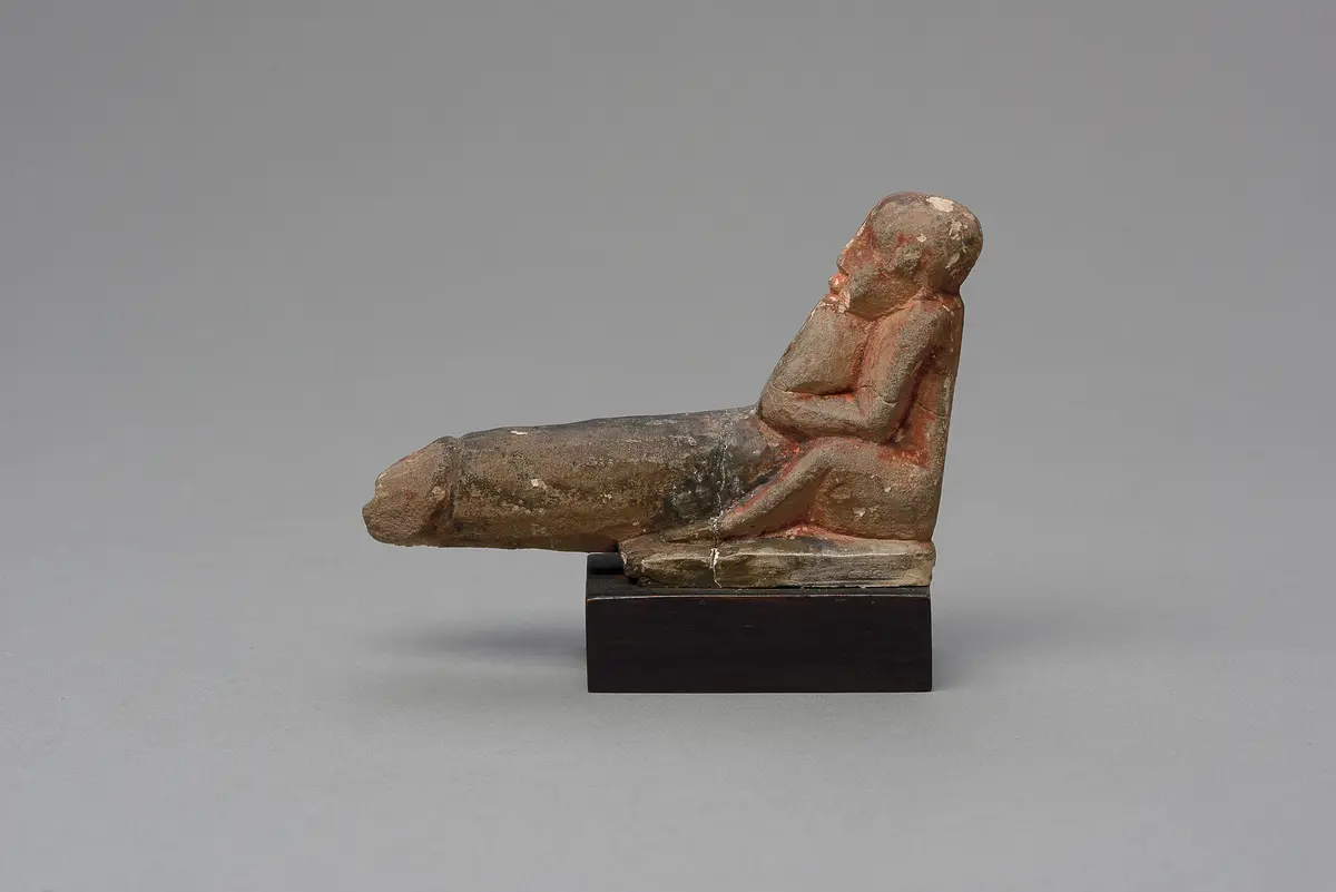 Hockender, nackter Mann mit übergroßem Phallus, eine Stele haltend