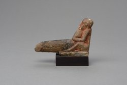 Hockender, nackter Mann mit übergroßem Phallus, eine Stele haltend