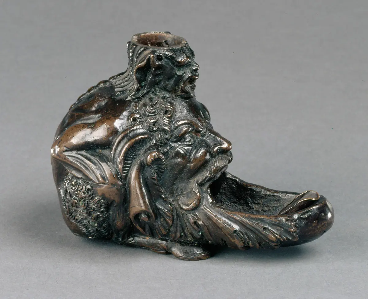Öllampe in Gestalt eines hockenden Satyrs mit groteskem Maskeron zwischen den Knien