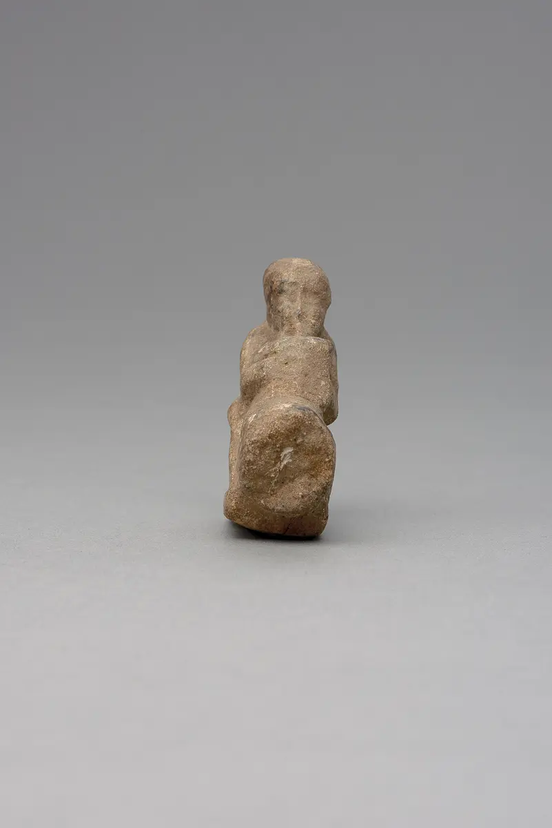 Hockender, nackter Mann, über seinem Phallus eine Stele haltend, fragmentiert