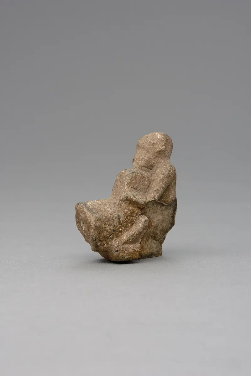 Hockender, nackter Mann, über seinem Phallus eine Stele haltend, fragmentiert