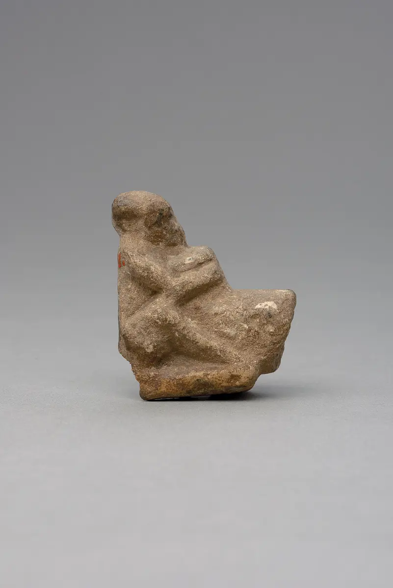 Hockender, nackter Mann, über seinem Phallus eine Stele haltend, fragmentiert