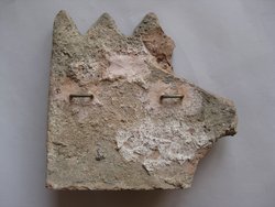 Fragment einer Krönung mit Theatermasken im Bogenfries: zwei Masken und Bögen unter Zierstreifen