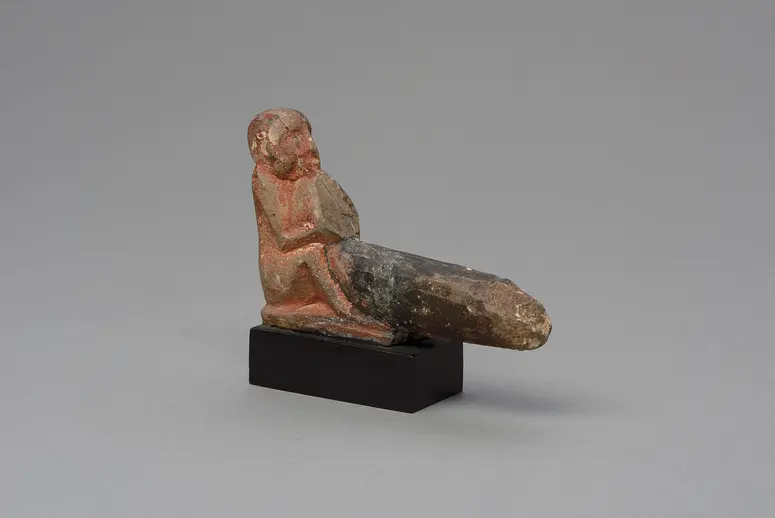 Hockender, nackter Mann mit übergroßem Phallus, eine Stele haltend