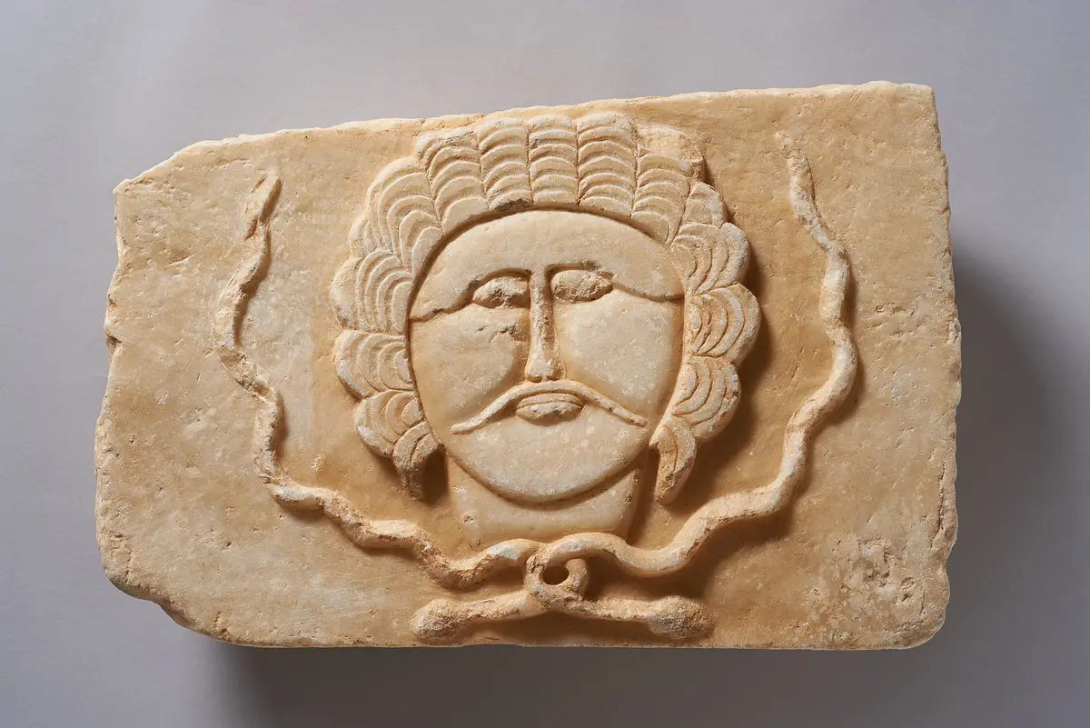Relief eines Mannes mit Schnurrbart und Haarkranz