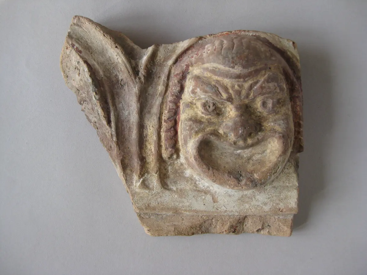 Fragment einer Krönung mit Theatermasken im Bogenfries: Maske und Ansatz eines zweiten Bogens