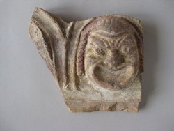 Fragment einer Krönung mit Theatermasken im Bogenfries: Maske und Ansatz eines zweiten Bogens